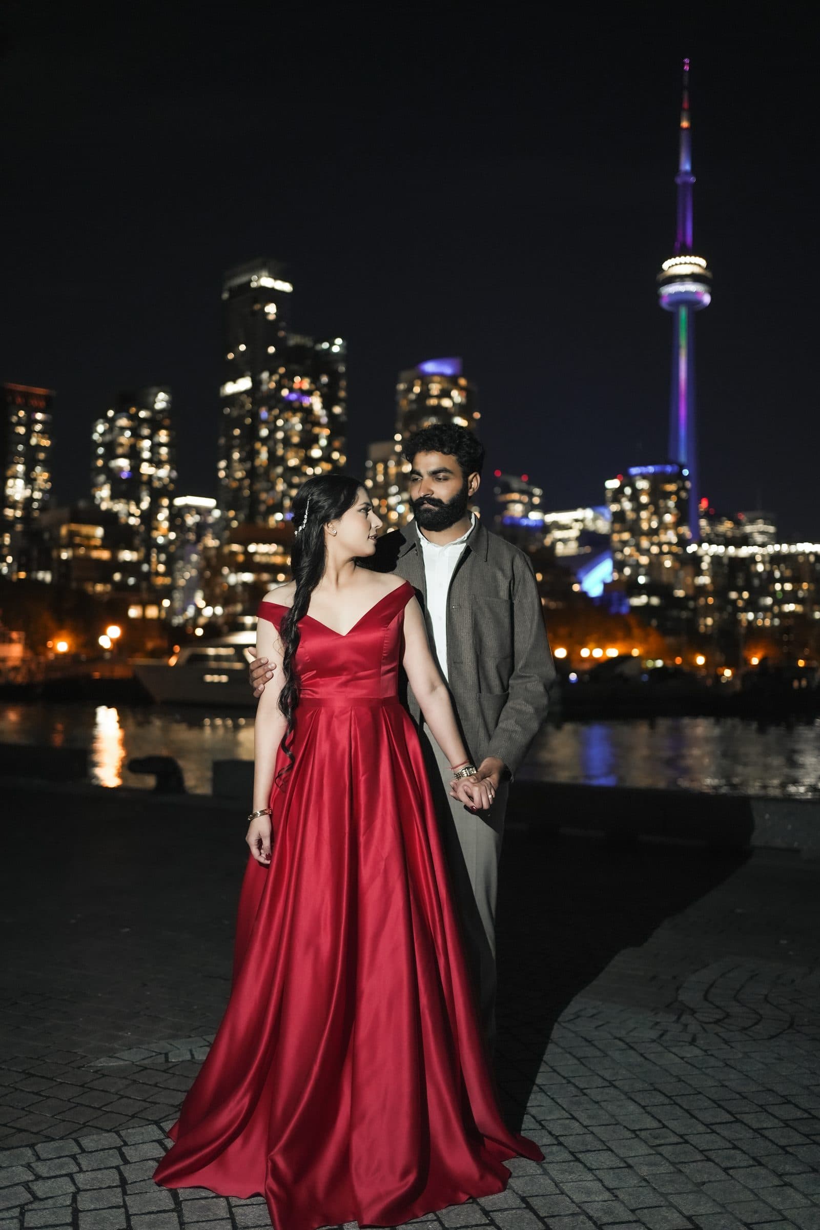 A couple photographed against a city skyline at night