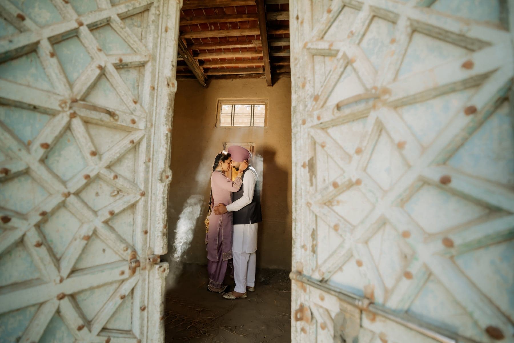 A couple embracing in a sunlit doorway, incense smoke drifting between them